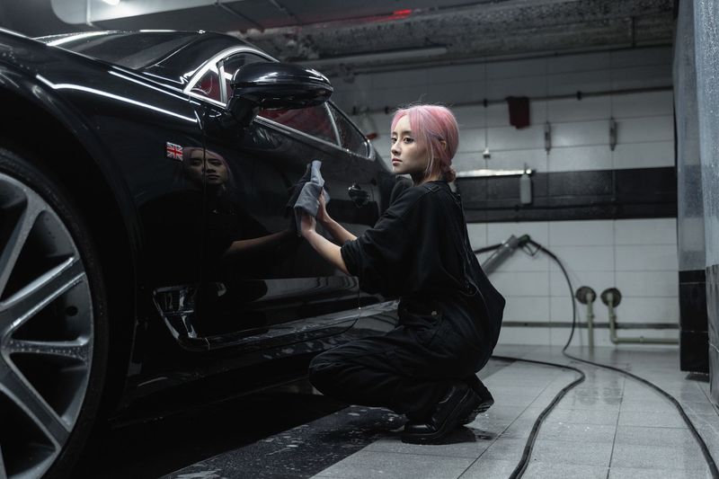 Detailer applying ceramic coating to a vehicle in a clean garage